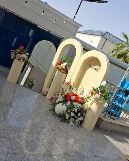 تنسيق وكوشة: ورد وأقواس وخلفية مجهزة للمناسبة.